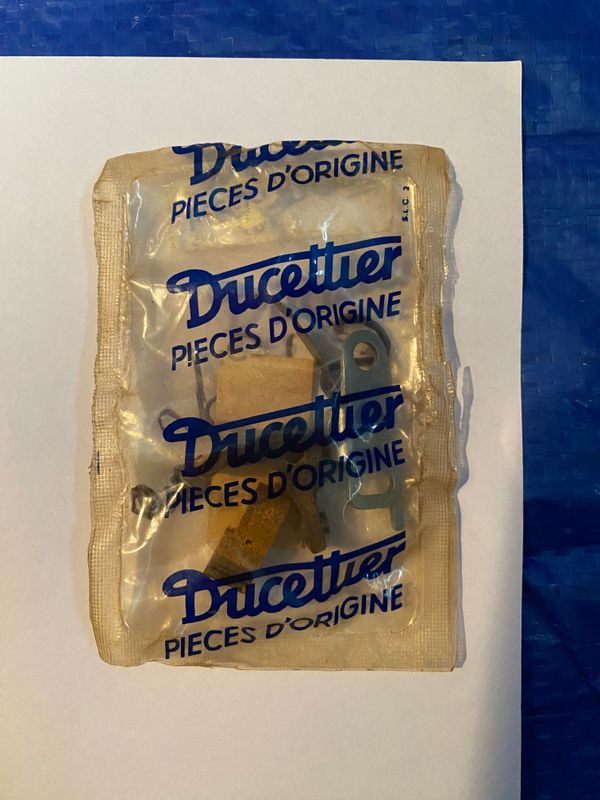 A set of 3 Peugeot 203 Ducellier ignition points enclosed in a clear plastic bag. These are a  set of electrical contacts that switch the coil on or off when the vehicle starts.