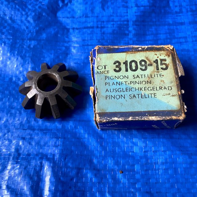 A Peugeot 203/403 diff pinion gear placed against a solid blue background. In original box with part number 310915. 