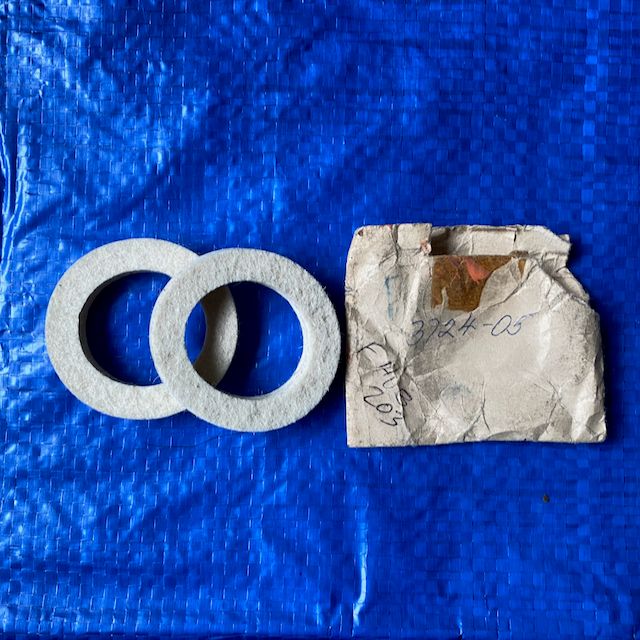 A pair of early Peugeot 203  front hub felt oilers placed against a solid blue background. The front hub felt oilers exclude dust and dirt.