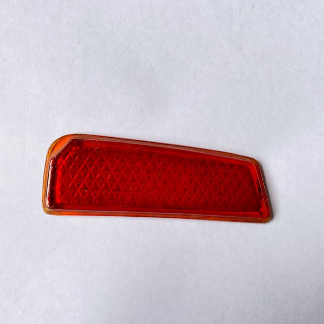 An early Peugeot 203 rear tail light lens placed against a white background. The purpose of the tail light is to protect the light bulb from the external environment.