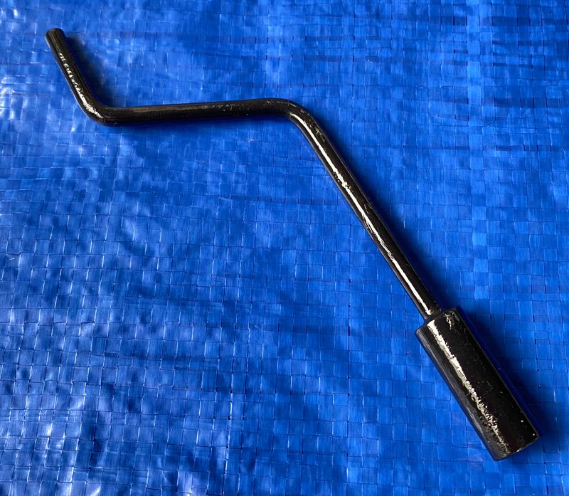 A Peugeot 203 emergency windscreen crank handle placed against a solid blue background. The windscreen crank handle is to open and close a car window: 