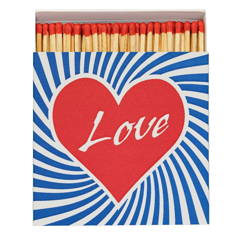Love Matches by Archivist Gallery, offered by Maison Maeva, featuring a red heart and blue-white stripes around it in bright colors, inspired by 1970s style. Contains 100 matches (100 mm) in a 110 x 110 x 50 mm box.