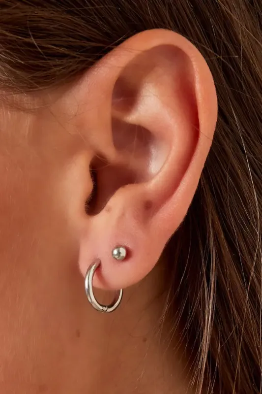Close-up view of the gold-plated hoop earrings (XS size) worn in the ear, showcasing the minimalist design.