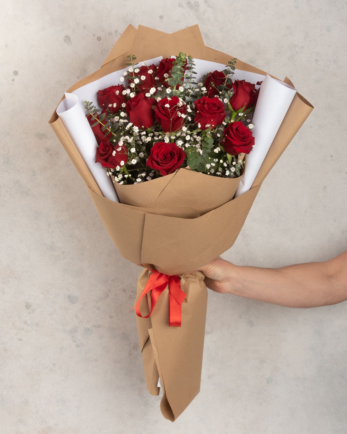 A bouquet of roses for a gift. A bouquet of 12 long-stemmed red roses, decorated with foliage and gypsophila, and arranged in colorful Korean paper.