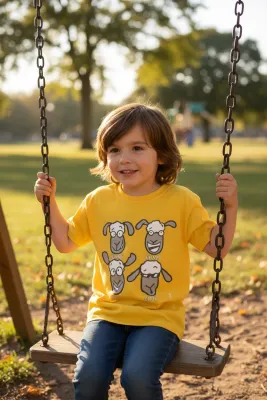 Child on swing smiling with yellow t-shirt and illustrations of funny sheep faces