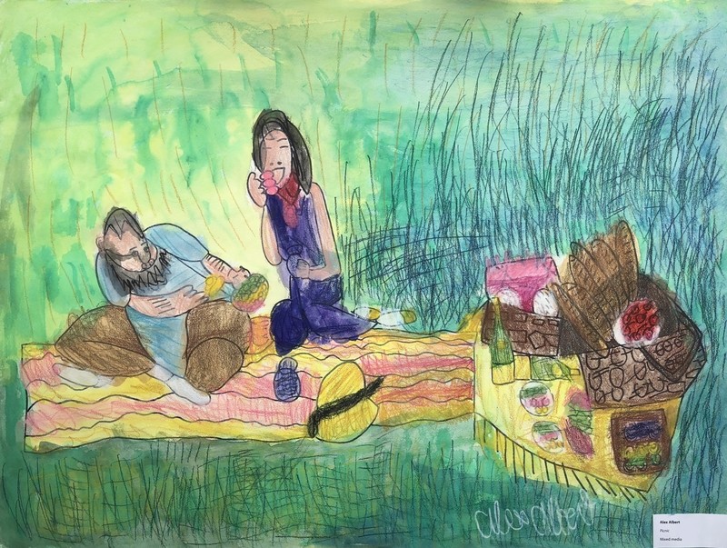 A man and a woman are seated on a red-and-yellow striped picnic blanket over the green grass. The man is sitting cross-legged on the left side of the frame, and he has a dark gray beard, short hair, a long blue t-shirt, and brown pants. He is leaning over to the left as he holds his food. The woman on the right is smiling and holding her food up to her mouth, and she is wearing a sleeveless indigo dress with a red tie scarf. Her hair is black and shoulder-length. A yellow picnic basket sits in the center of the blanket in front of them, and a large assortment of food including bread, wine, and platters can be seen off the right edge of the frame.