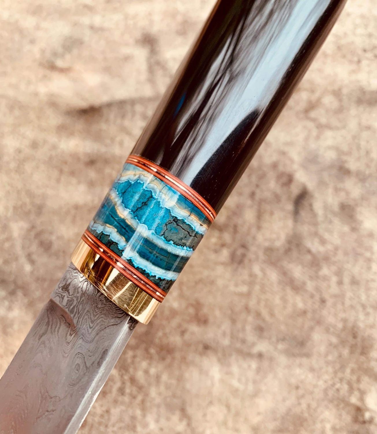 Custom knife featuring a stabilized mammoth tooth spacer between the bolster and handle material, showcasing the unique fossil pattern and premium craftsmanship.