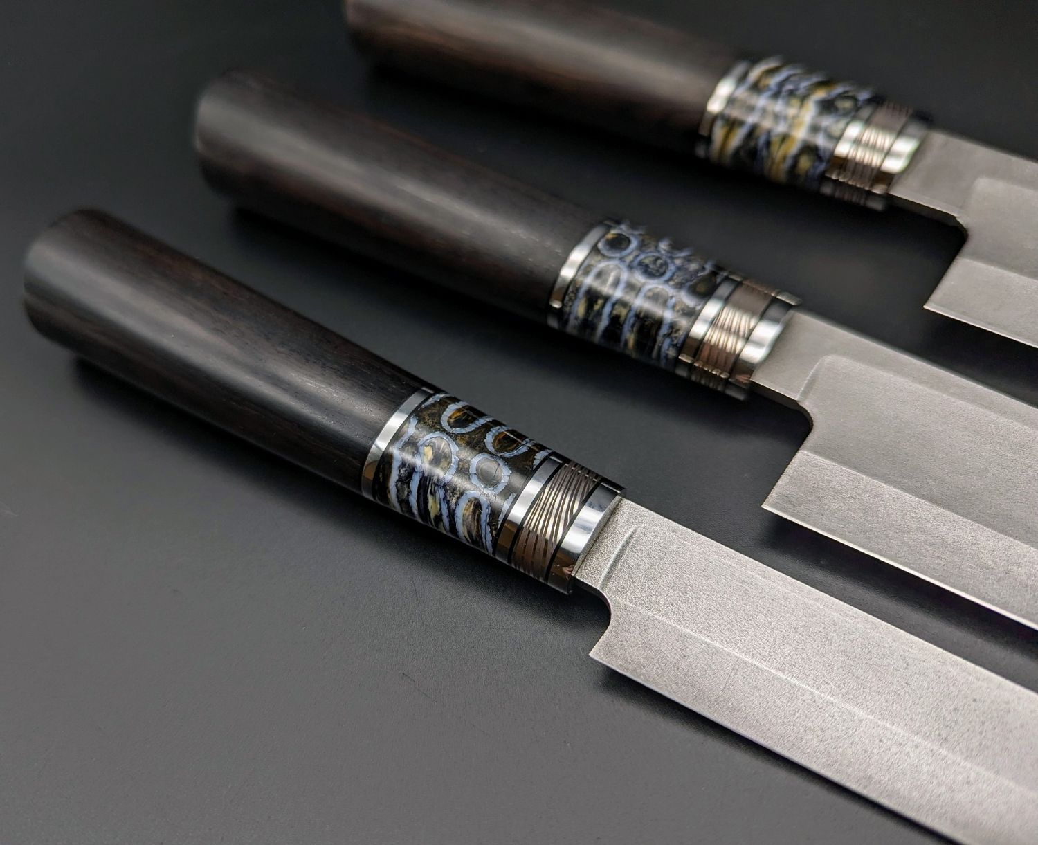 Handcrafted custom knife with a colorful stabilized mammoth tooth spacer, highlighting the natural fossil structure and unique handle construction.