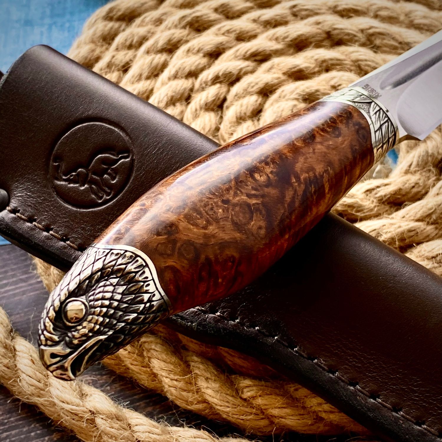 Knife with an Amboyna burl wood handle featuring dense burl eyes and swirling natural grain patterns.
