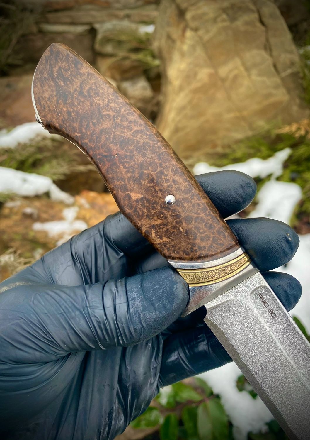 Custom fixed blade knife with a figured Amboyna burl handle in warm reddish-brown and golden tones.