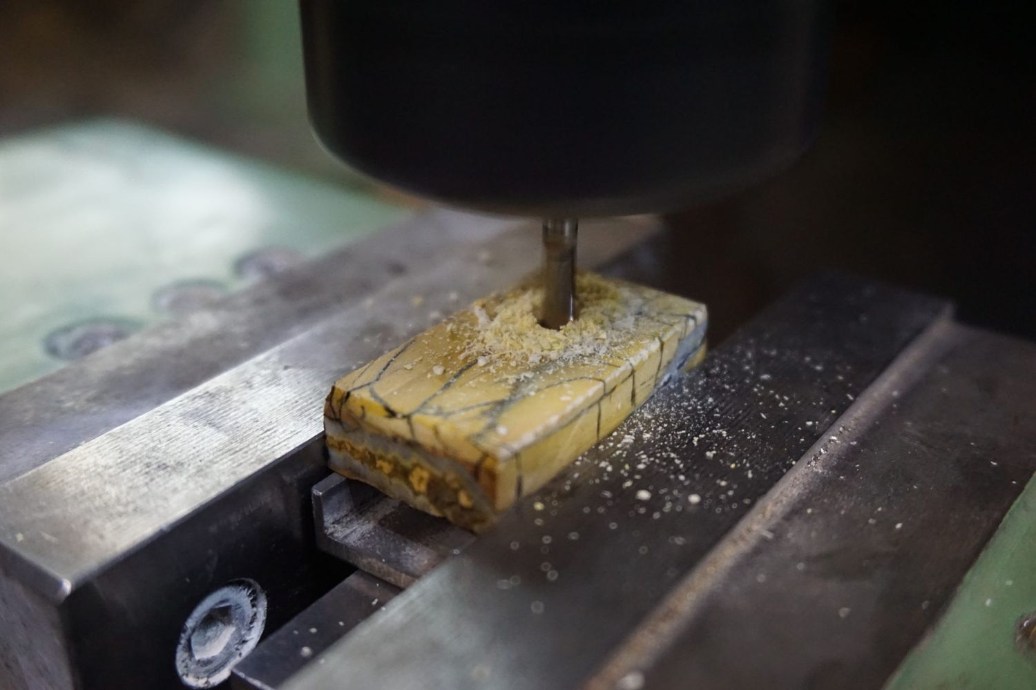 Stabilized mammoth tooth block clamped in a vise being drilled
