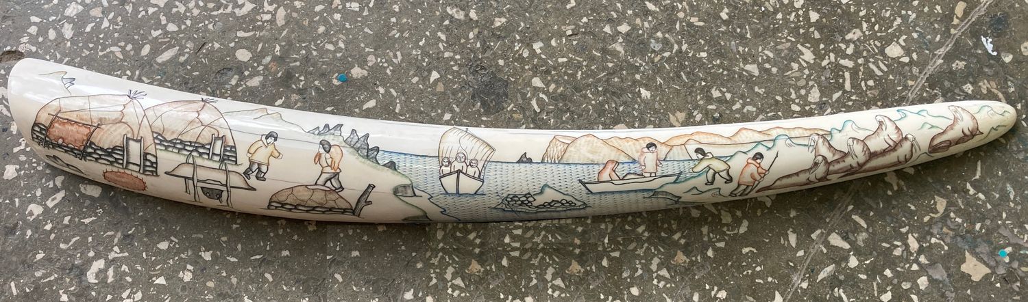 Traditional scrimshaw engraving by a Uelen master on walrus ivory, depicting scenes of Eskimo daily life, hunting activities, sled dogs, and Arctic coastal traditions.