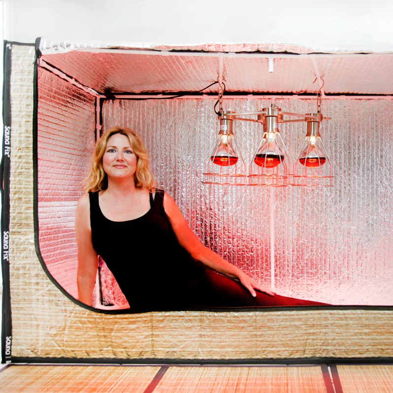 Woman relaxing inside a spacious Sauna Fix near infrared hot yoga and exercise sauna tent