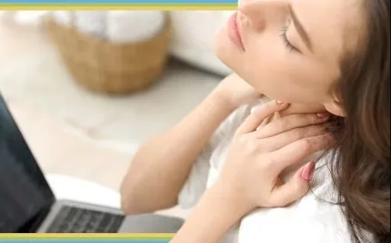 Person holding neck while using a laptop