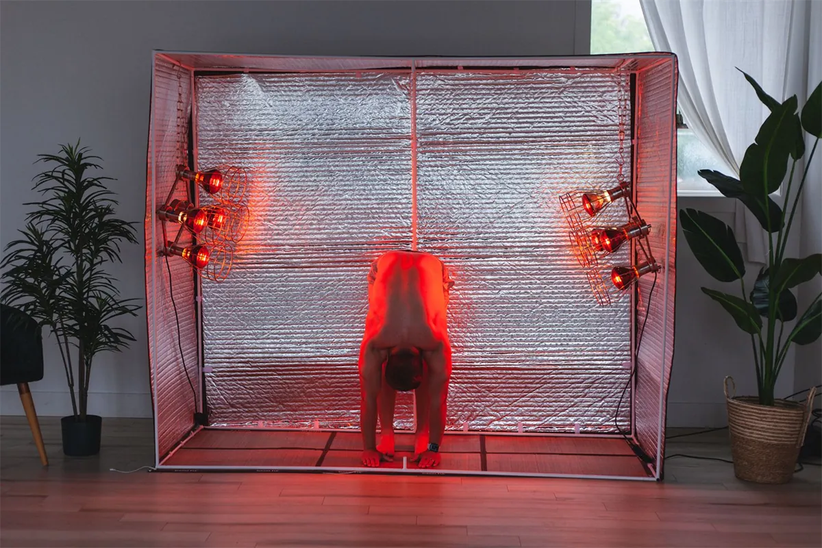 Deep yoga fold under near infrared lamps in the hot yoga sauna tent