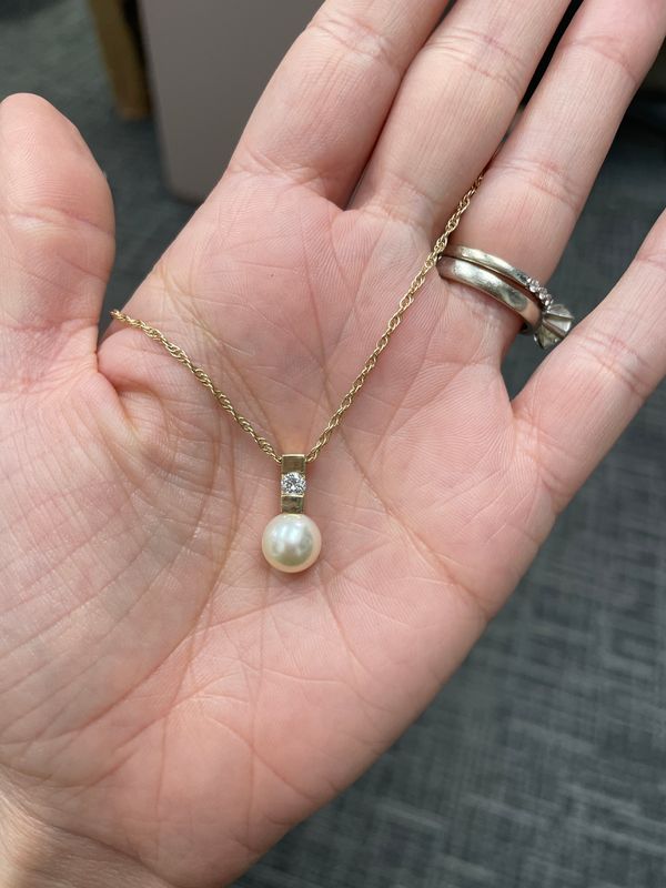 gold pearl necklace featuring a delicate chain with a single pearl hanging from a gold bale accented by a round diamond