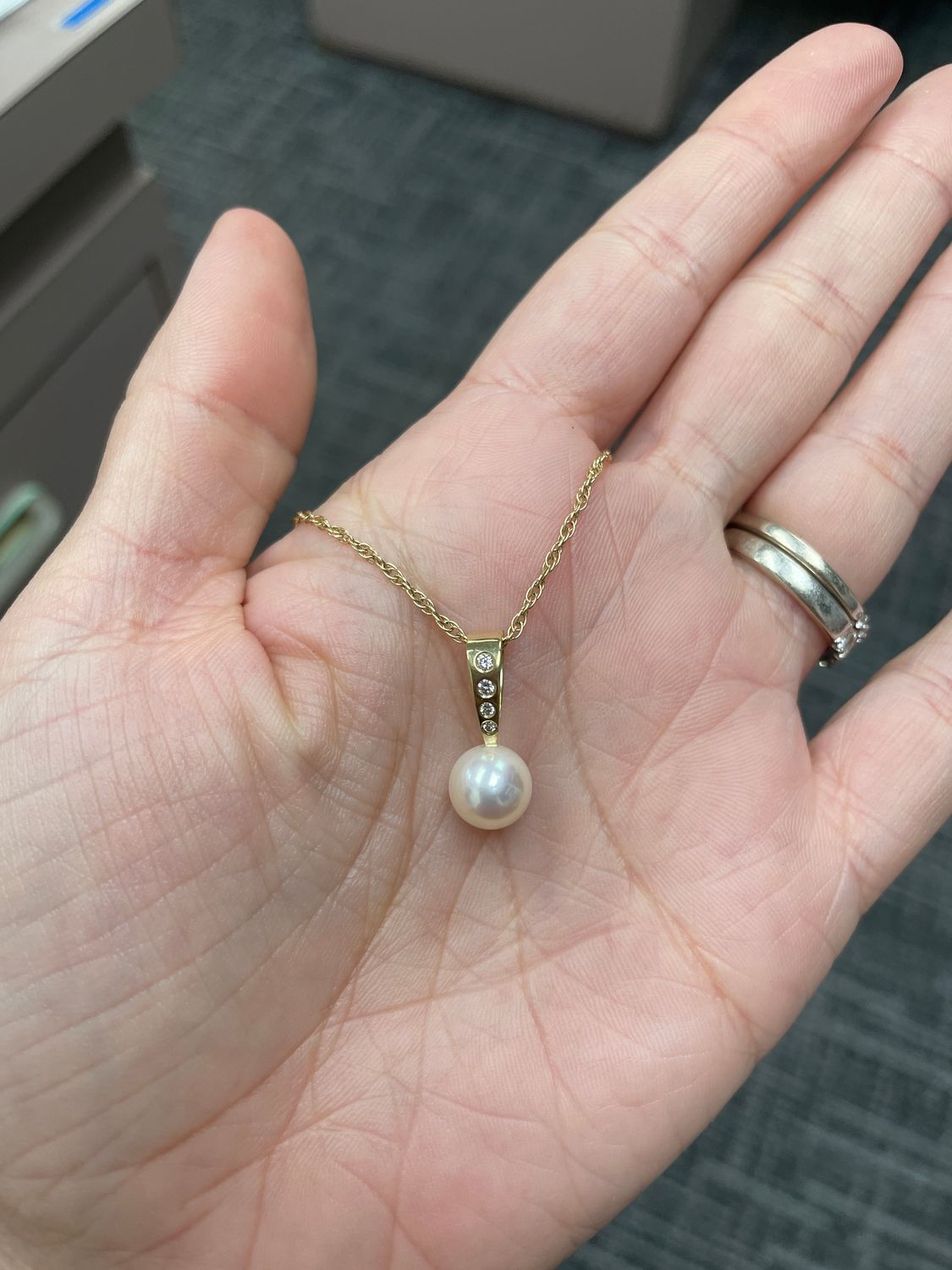 Pearl necklace set in 14K yellow gold with 4 round diamonds above. On a yellow gold chain. 