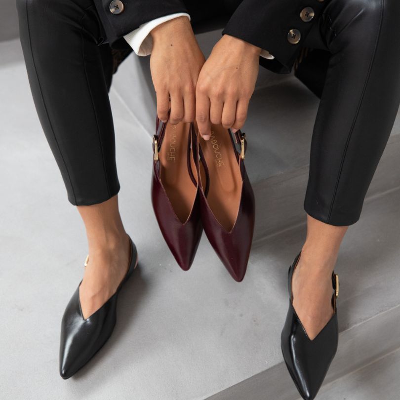 dame met bordeaux slingbacks in de hand