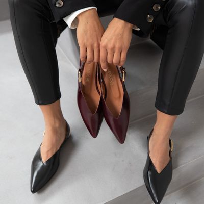 dame met bordeaux slingbacks in de hand