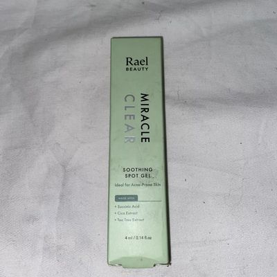 A small, rectangular, mint-green box labeled “Rael Beauty Miracle Clear Soothing Spot Gel” standing upright against a neutral background. The box features minimal text and simple graphics, indicating key ingredients and usage instructions.
