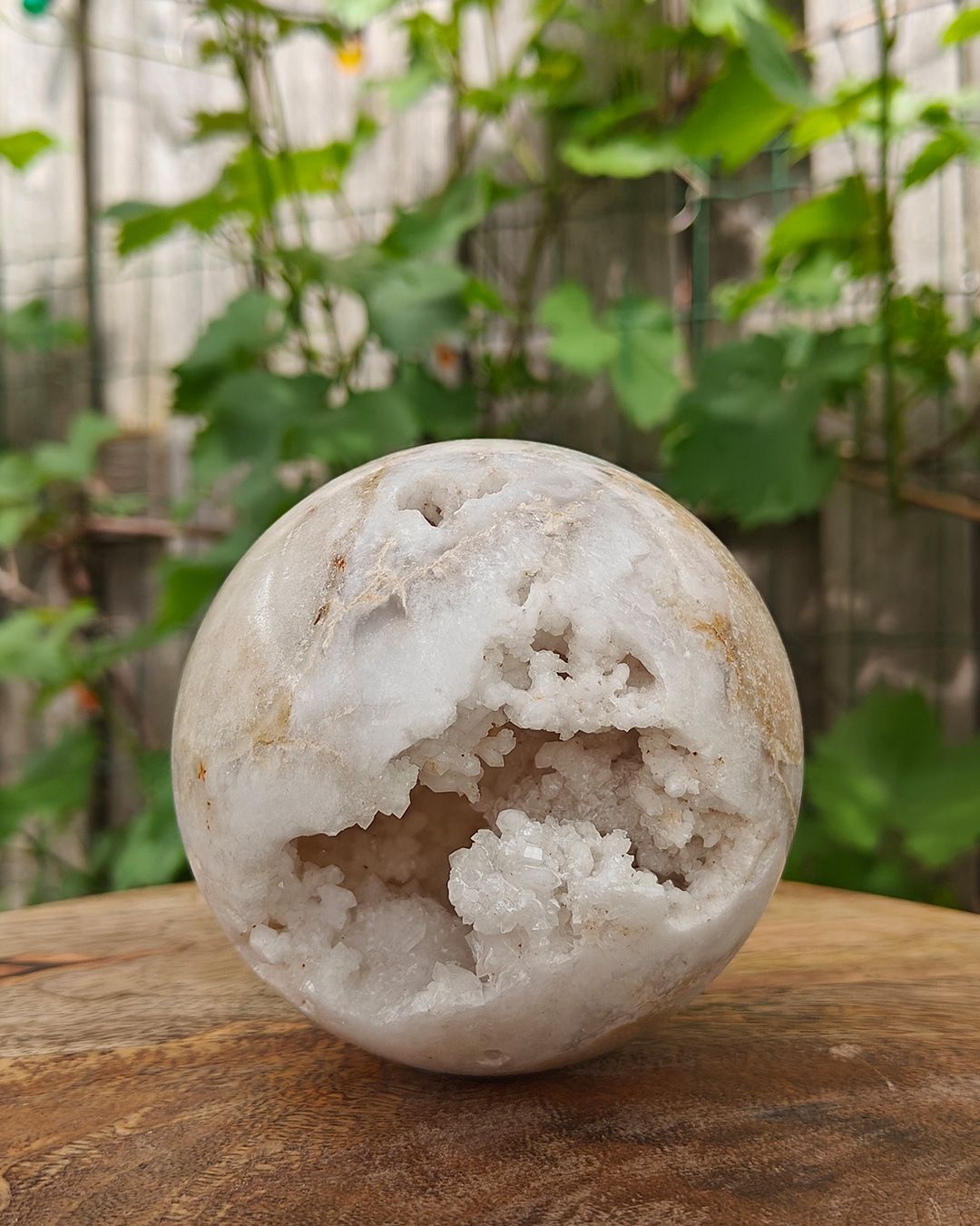 Marokkaanse Agaat Druzy Bol – 9,5 cm Marokkaanse agaat bol met natuurlijke druzy-opening en fonkelende kristallen op houten ondergrond
