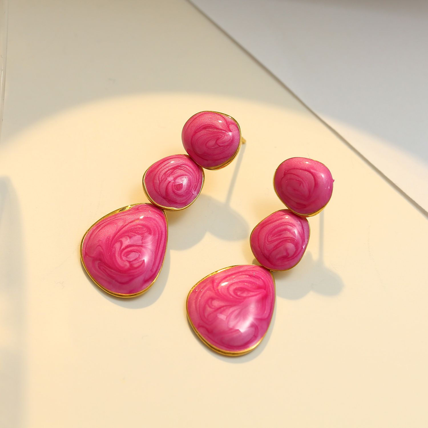 Goudkleurige hangende oorbellen met roze emaille