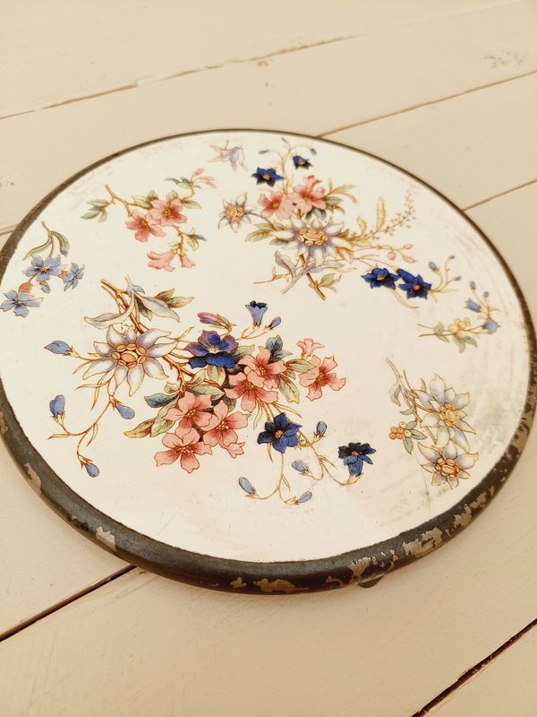 Antieke onderzetter met beige ondergrond, bloemen en verzilverde rand