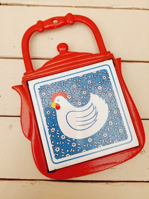 Rode metalen onderzetter theepot met tegel kip