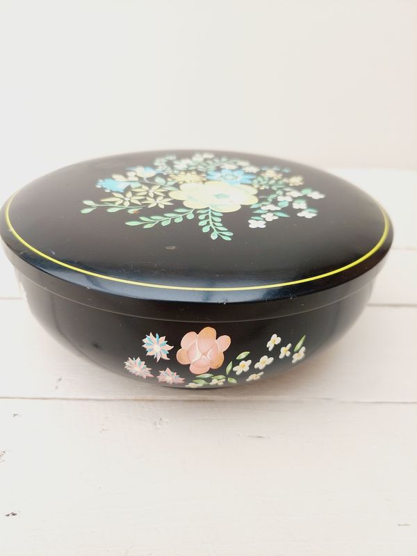 Vintage rond blik, zwart met bloemendecoratie