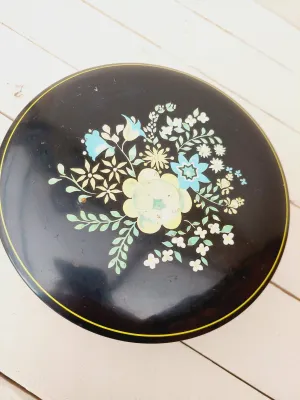 Vintage rond blik, zwart met bloemendecoratie