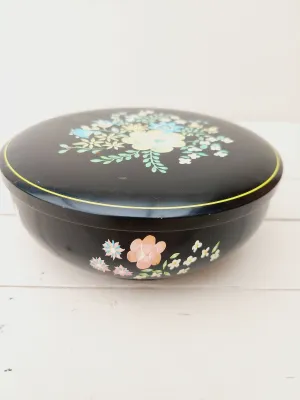 Vintage rond blik, zwart met bloemendecoratie