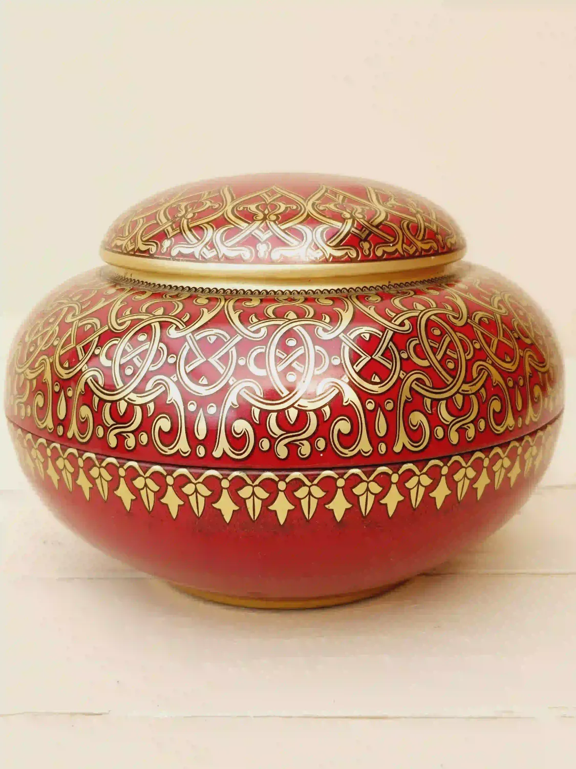 Vintage blik in Oosterse stijl, rond met rode basis en gouden sierlijke decoratie