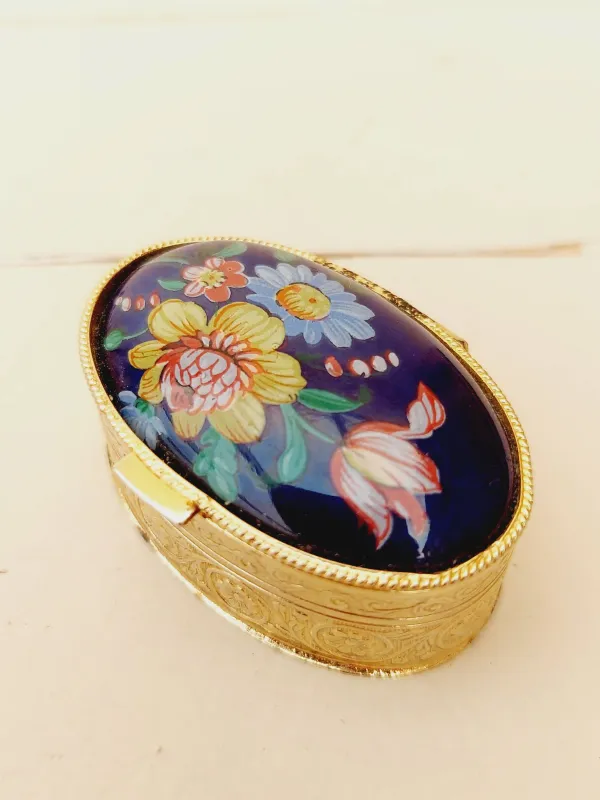 Vintage ovaal pillendoosje, blauw deksel met veldbloemen, goudkleurig doosje