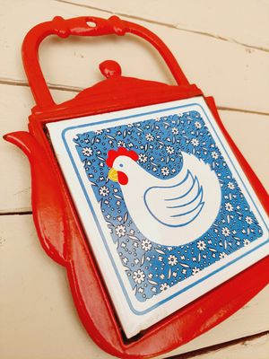 Rode metalen onderzetter theepot met tegel kip