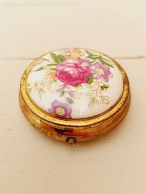 Vintage rond pillendoosje, wit deksel met kleurrijke bloemen, goudkleurig doosje