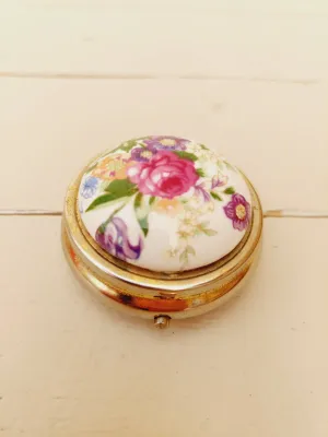 Vintage rond pillendoosje, wit deksel met kleurrijke loemen, goudkleurig doosje