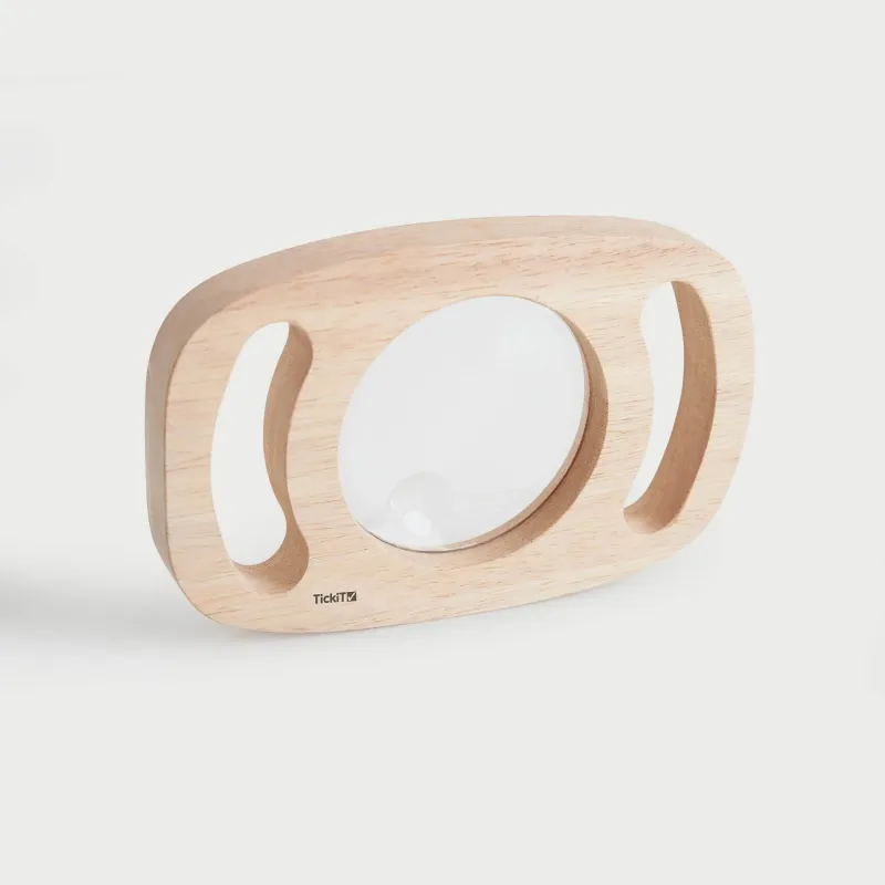 Close-up van het TickiT vergrootglas met houten frame en grote lens met twee comfortabele handgrepen.