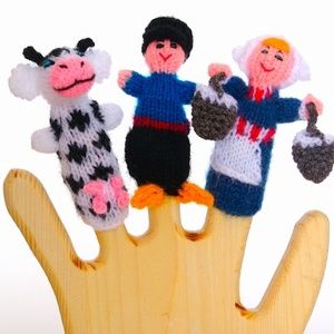 houten hand met daarop vingerpoppetjes koe, boer en boerin