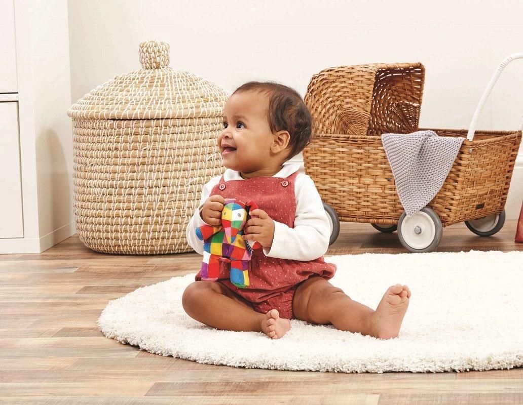 Kindje die met de Elmer Rammelaar Pluche 12 cm Rainbow Designs babyspeelgoed speelt