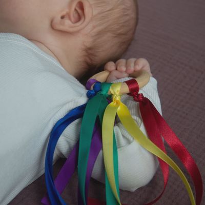 Little Botanic Label Baby handvlieger groen/blauw – babyspeelgoed die vastgehouden word door een baby.