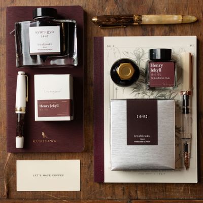 Flat lay of brown ink bottles, fountain pens, and notebooks styled for a cozy, slow morning writing ritual.