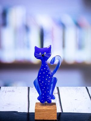 Glasfigur Kat, blå med hvide pletter, hale til højre, på træfod