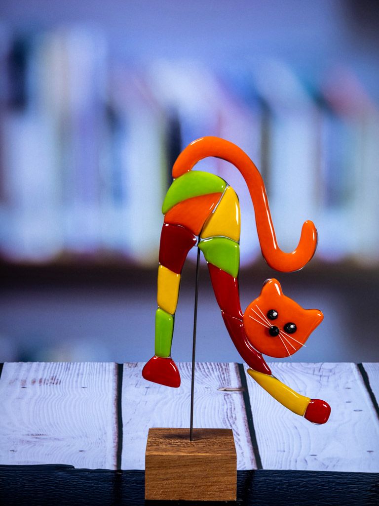Glasfigur Kat, strækker sig, gul, rød, orange, grøn, med orange hoved, på træfod