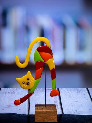 Glasfigur Kat, strækker sig, gul, rød, orange, grøn, med gult hoved på træfod