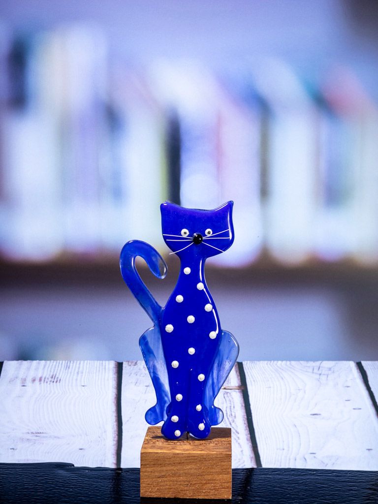 Glasfigur Kat, blå med hvide pletter, hale til venstre, på træfod