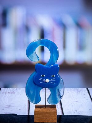 Glasfigur Kat, lyseblå, siddende, kroget hale, på træfod