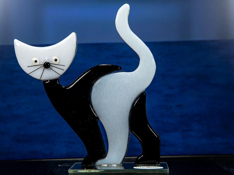 Glasfigur, sort hvid, med hvidt hoved, går mod venstre, på glasfod