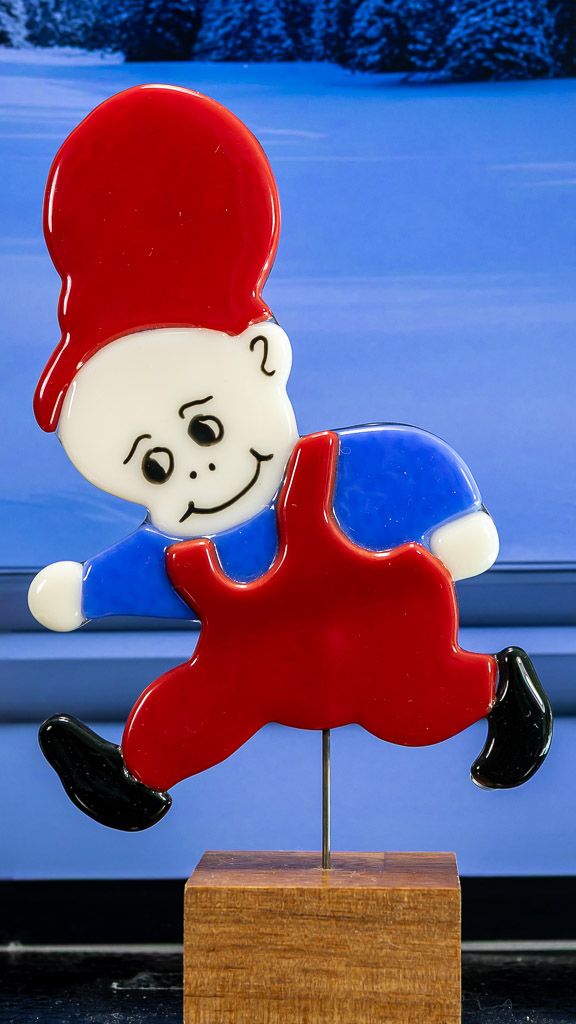 Glasfigur Nissedreng med blå bluse, løber mod venstre, på træfod