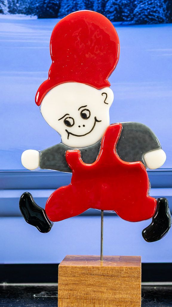 Glasfigur Nissedreng med grå bluse, løber mod venstre, på træfod