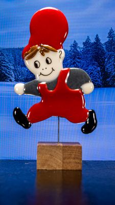 Glasfigur Nissedreng med grå bluse, løber mod venstre, på træfod Glasfigur Nissedreng med grå bluse, løber mod venstre, på træfod